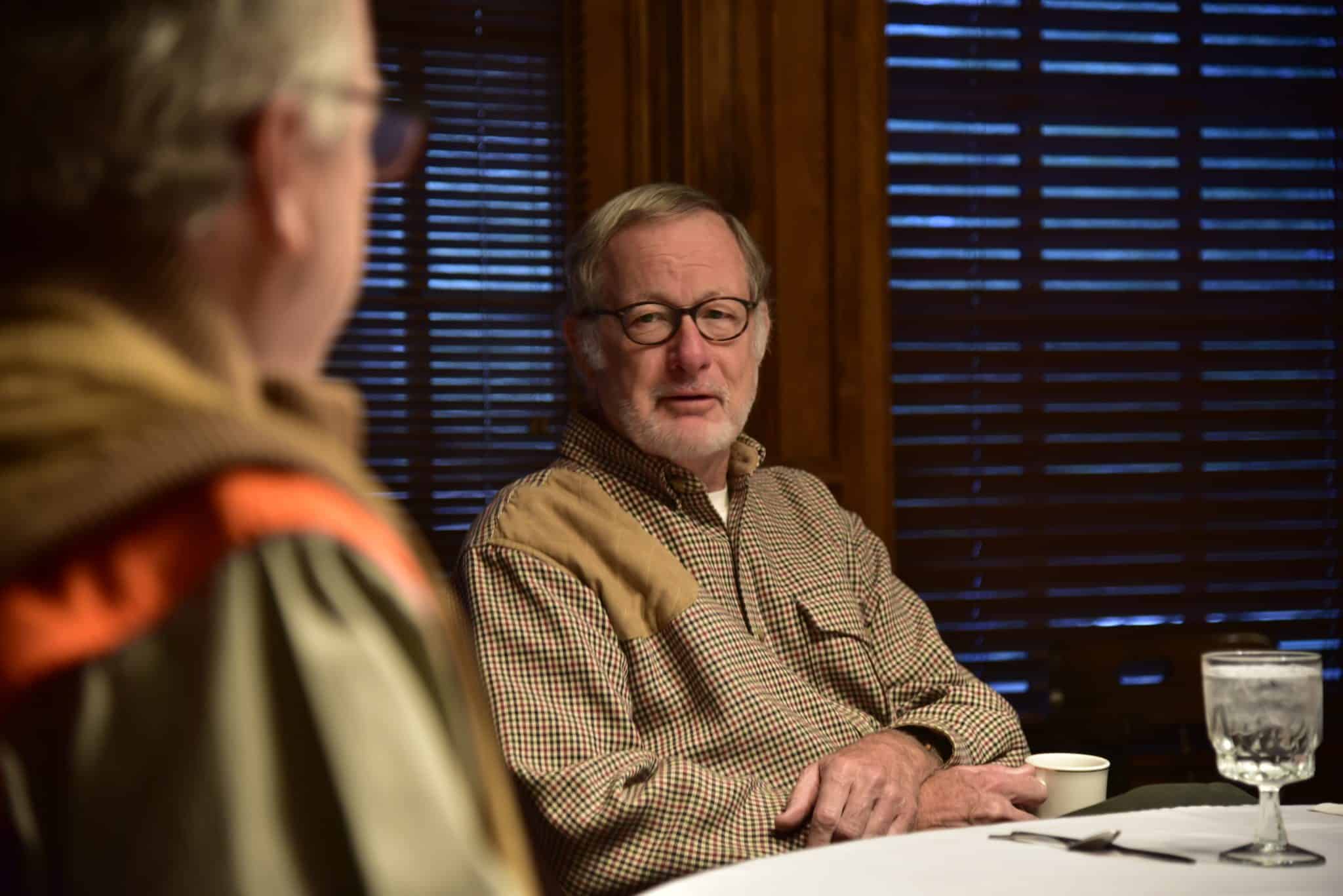 man with glasses and beard talking to another
