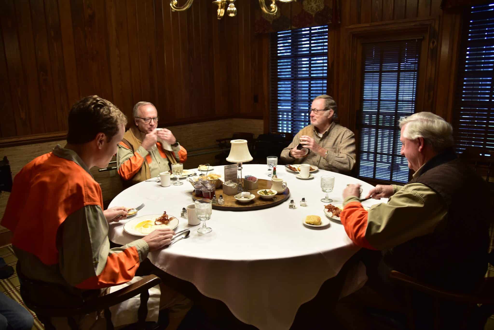 4 men gathered eating breakfast at Riverview Plantation