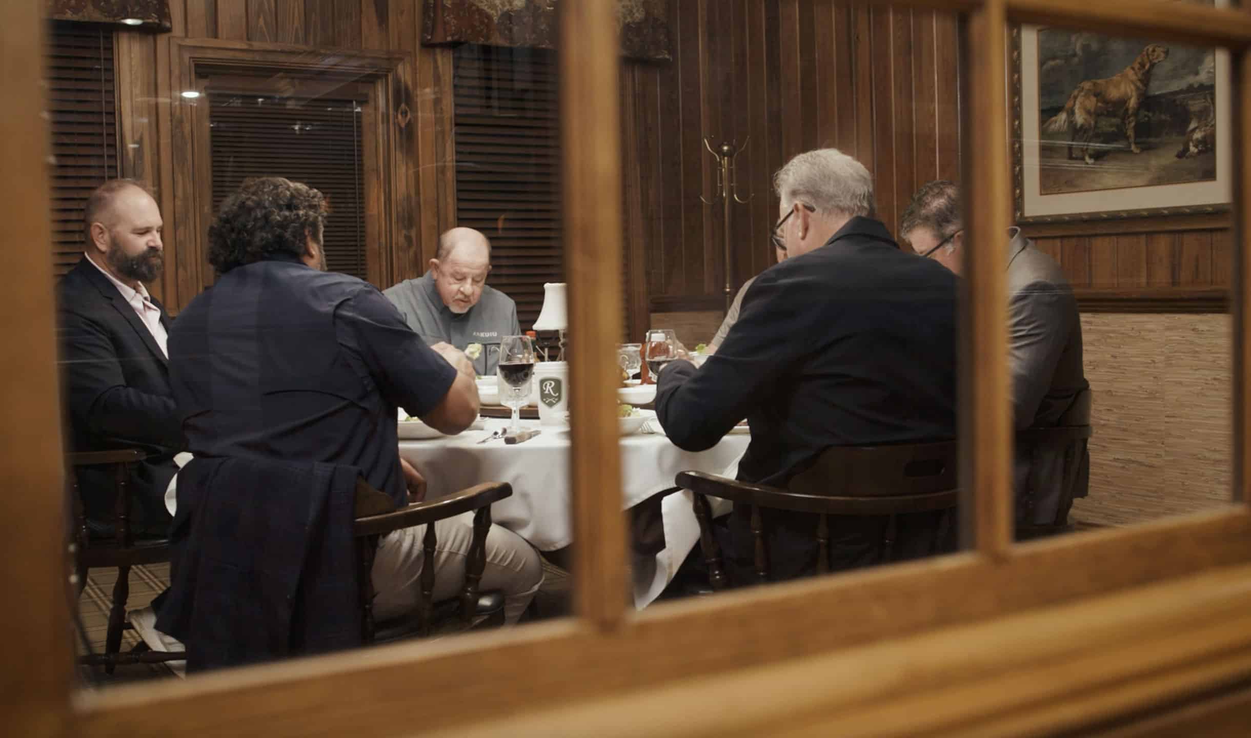 five men at a table enjoing dinner