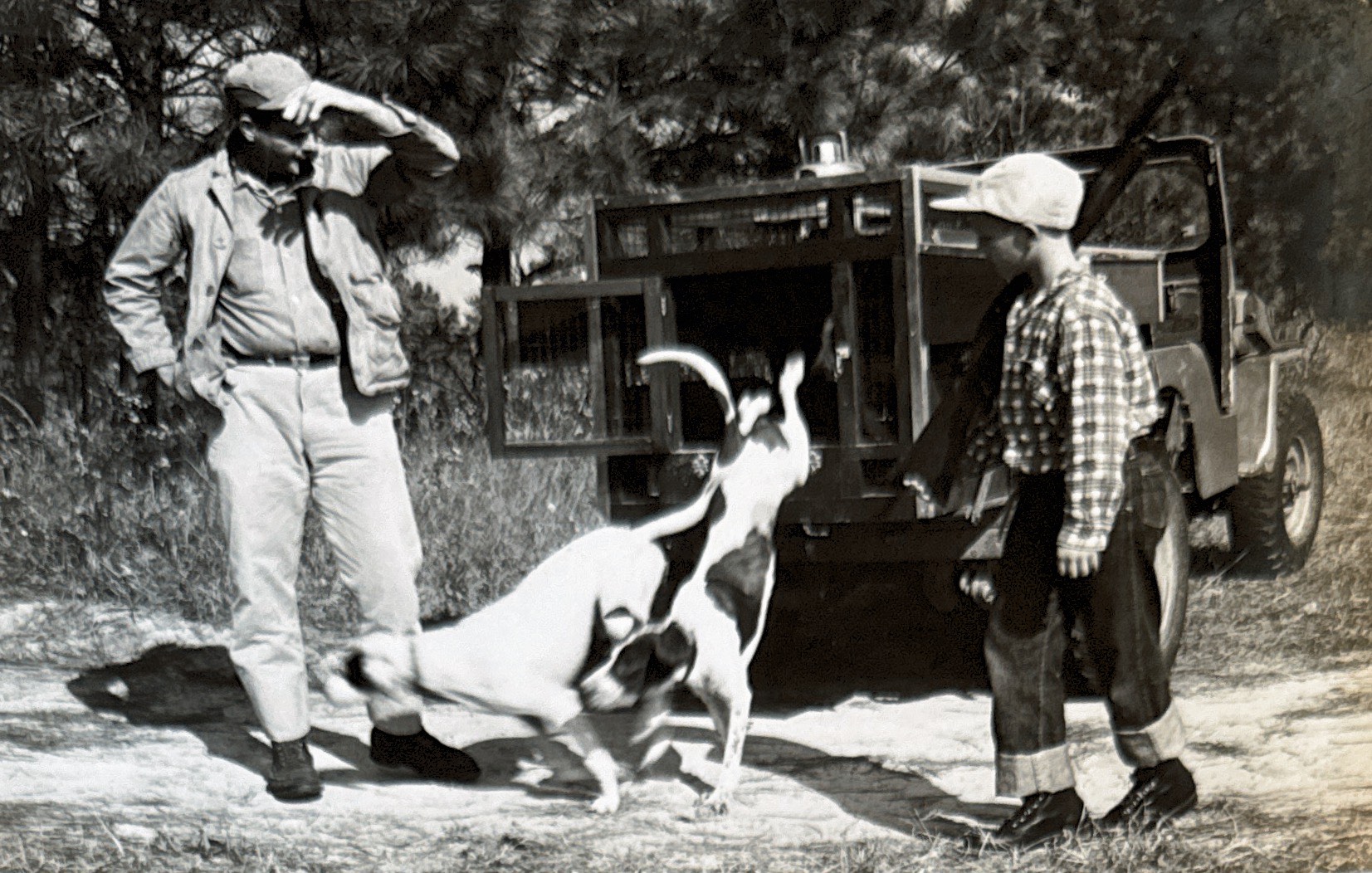 old image of a man and young boy letting dogs out